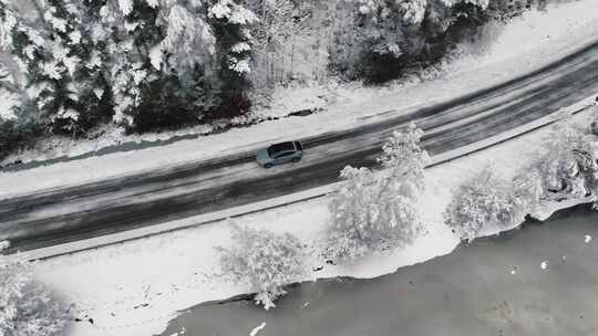 无人驾驶飞机拍摄的汽车在冬季森林道路上行