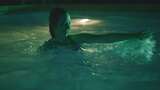 女人在绿色灯光的游泳池里把男人浸泡在水下高清在线视频素材下载