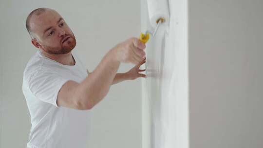 男人用滚筒粉刷白墙
