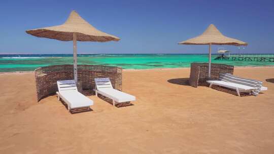 美丽蔚蓝大海背景下的海滩，配有雨伞和日光躺椅