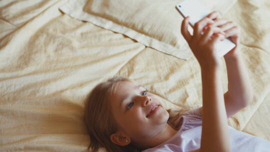 女孩躺在床上玩智能手机