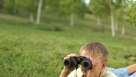 草地上拿双筒望远镜的男孩