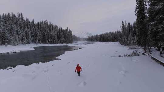 航拍男人艰难地走在新疆喀纳斯河边的雪地里