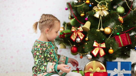 女孩在圣诞树下挑选礼物