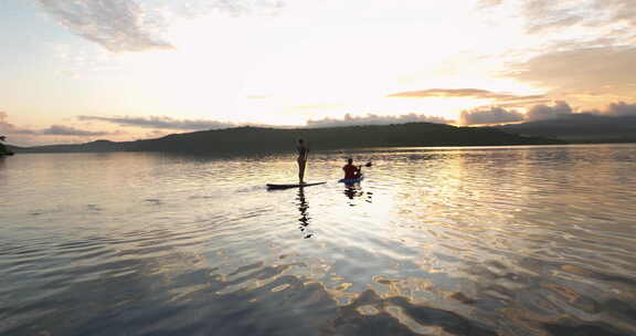 日出时，瓦努阿图莫索岛的一对夫妇在桨板和
