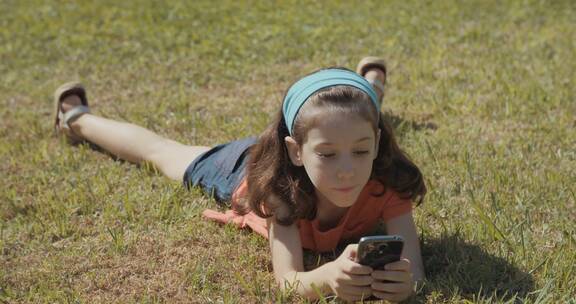 女孩开心的在草地上玩手机