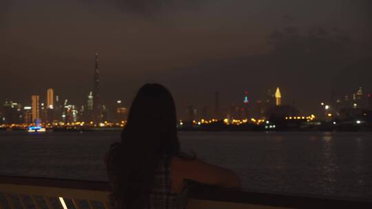 女人在海边欣赏城市夜景