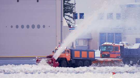 国际机场航站楼和跑道上装有扫雪机的卡车清