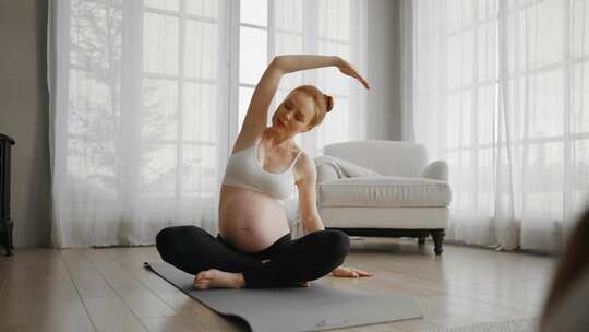 年轻孕妇在家做瑜伽大肚子孕妇练习瑜伽冥想