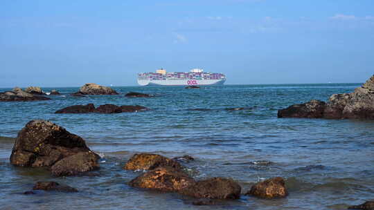 在海岸边的礁石上看远处慢慢驶过的巨型邮轮