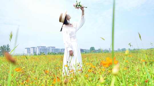 女子手持草帽漫步花海