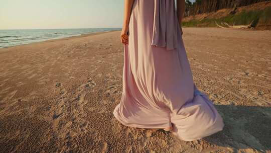 大角度跟随穿着长裙的美女在日落海背景下走在湿沙滩上