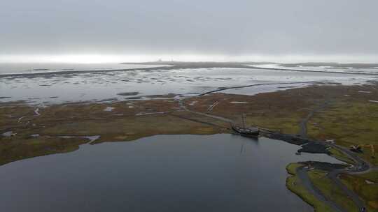 无人驾驶飞机飞越停泊在冰岛维斯特拉霍恩黑沙滩泻湖中的维京船