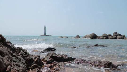晴天下的海上灯塔和冲向岸边的浪花