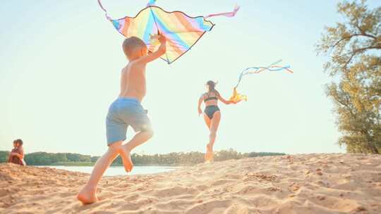 手拿风筝孩子们在沙滩上奔跑的