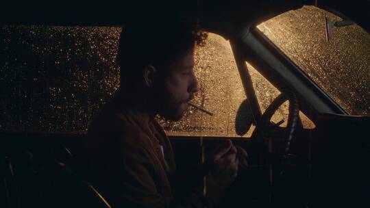 下雨天汽车里吸烟的男人