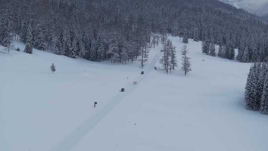 航拍汽车行驶在新疆喀纳斯大雪覆盖的公路上