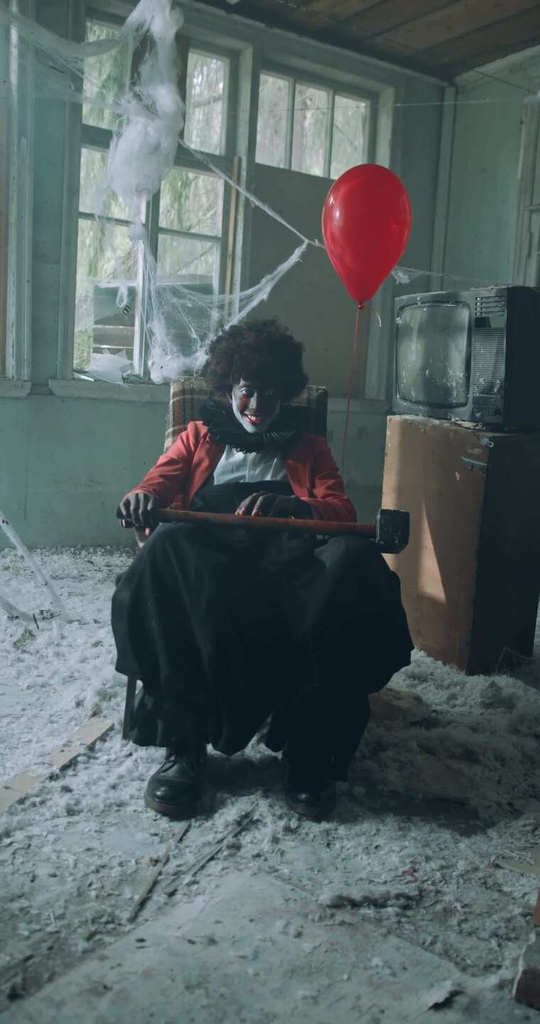 令人毛骨悚然的微笑小丑和锤子坐在一起