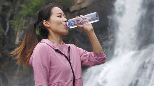 亚洲中国人女性在瀑布下喝水饮用水