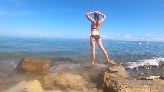 美女站在海浪拍打的海岸上视频素材模板下载