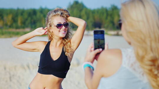 女人用手机在海滩上拍照