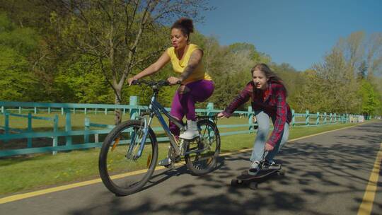 骑单车的女子和滑滑板的女孩