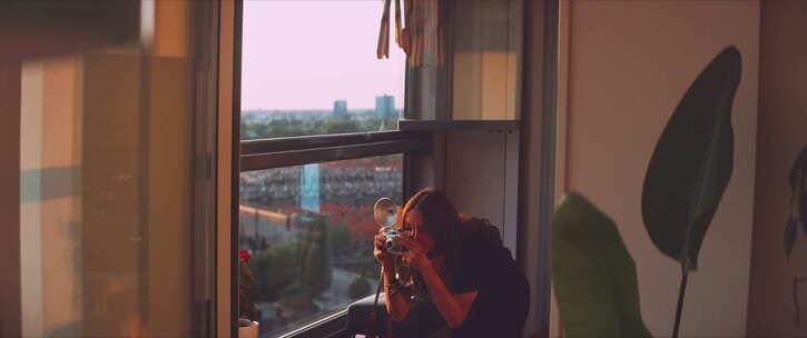 女摄影师在阳台上给一株植物拍照
