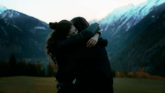 两个女孩在雪山边拥抱