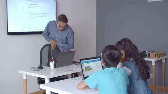 计算机科学老师在课堂上站在办公桌前