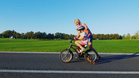 妈妈教女孩骑自行车的概念视频素材模板下载