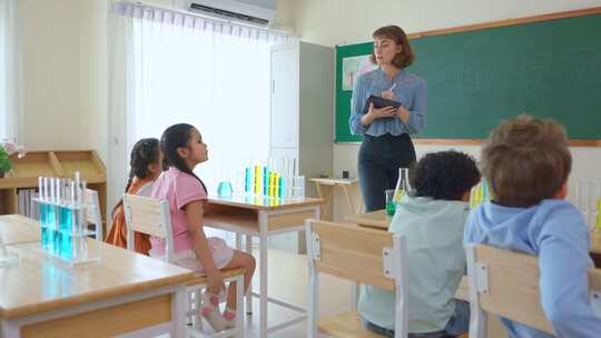 可爱的学生在小学教室里和老师一起学习。