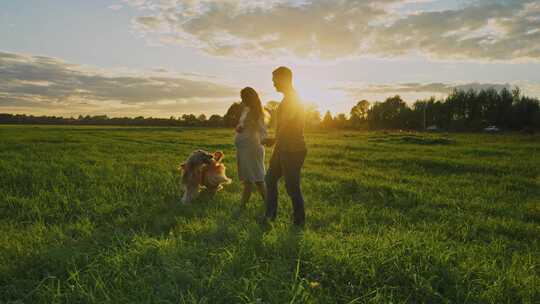 一对夫妇和他们的金毛猎犬在草地上享受日落