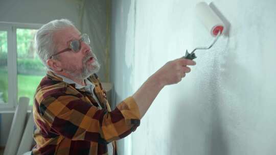 老人用白色油漆粉刷墙壁视频素材模板下载
