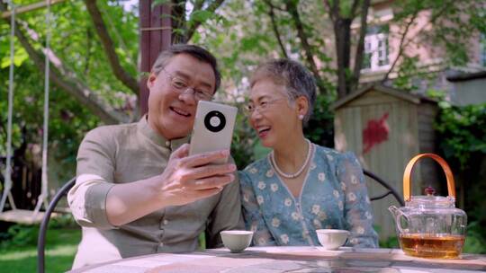 老年夫妇坐在院子里使用手机