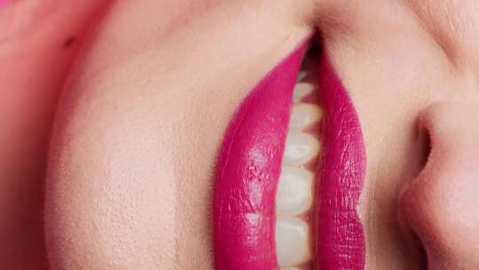 女人涂着粉色口红咬嘴唇