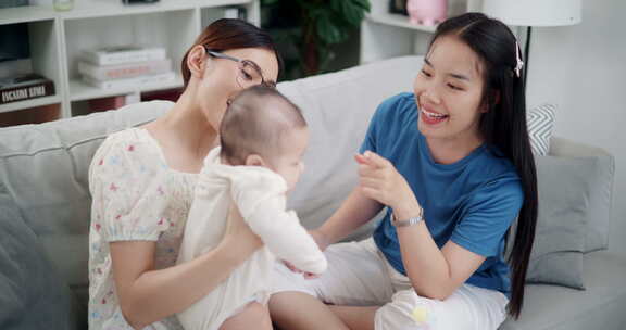 两个年轻的亚洲女人在家里开心地和一个婴儿