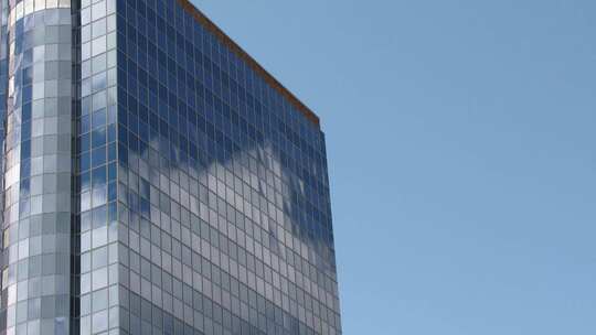 蓝天下的商业楼玻璃幕墙映照着白云流动