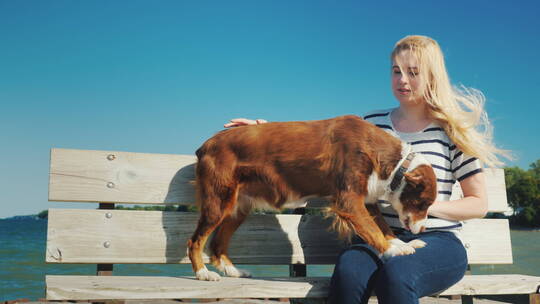海边长椅上的女人和她的狗