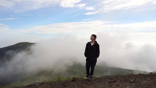 女性青年站在山顶看风景背影看远山感受自然