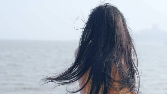 女孩在海边吹风，海风吹动头发飞扬