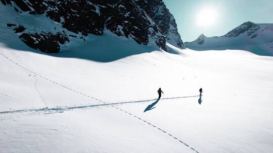 登山者在雪山脚下行走
