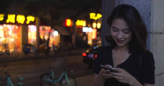 夜晚成都街头年轻女孩看手机上网发消息