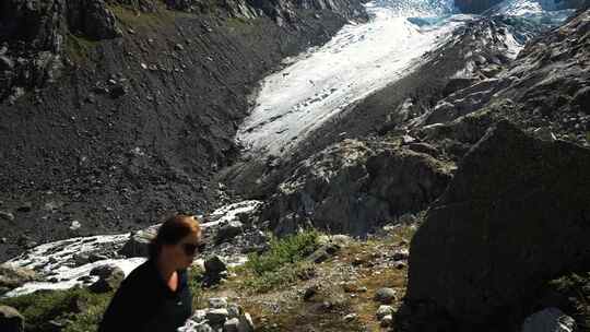 女孩正在冰川附近的高山徒步旅行，用瓶子喝