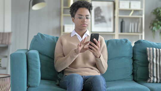 非洲女孩坐在沙发上使用电话