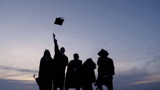 毕业生把帽子抛向空中的剪影