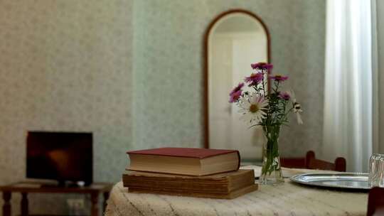 两本旧书，花瓶里的花和圆桌上银盘上的眼镜
