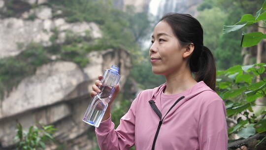 亚洲中国人女性在瀑布下喝水饮用水