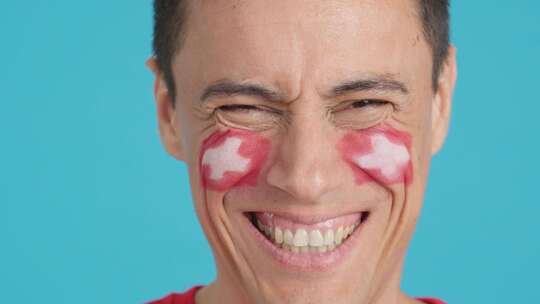 脸上画着瑞士国旗微笑的人