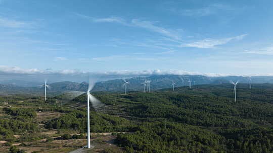 在一个拥有绿色森林和美丽蓝天的风力涡轮机农场上空的超光速拍摄。视差。