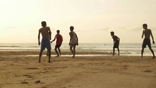 在沙滩上踢球的人群